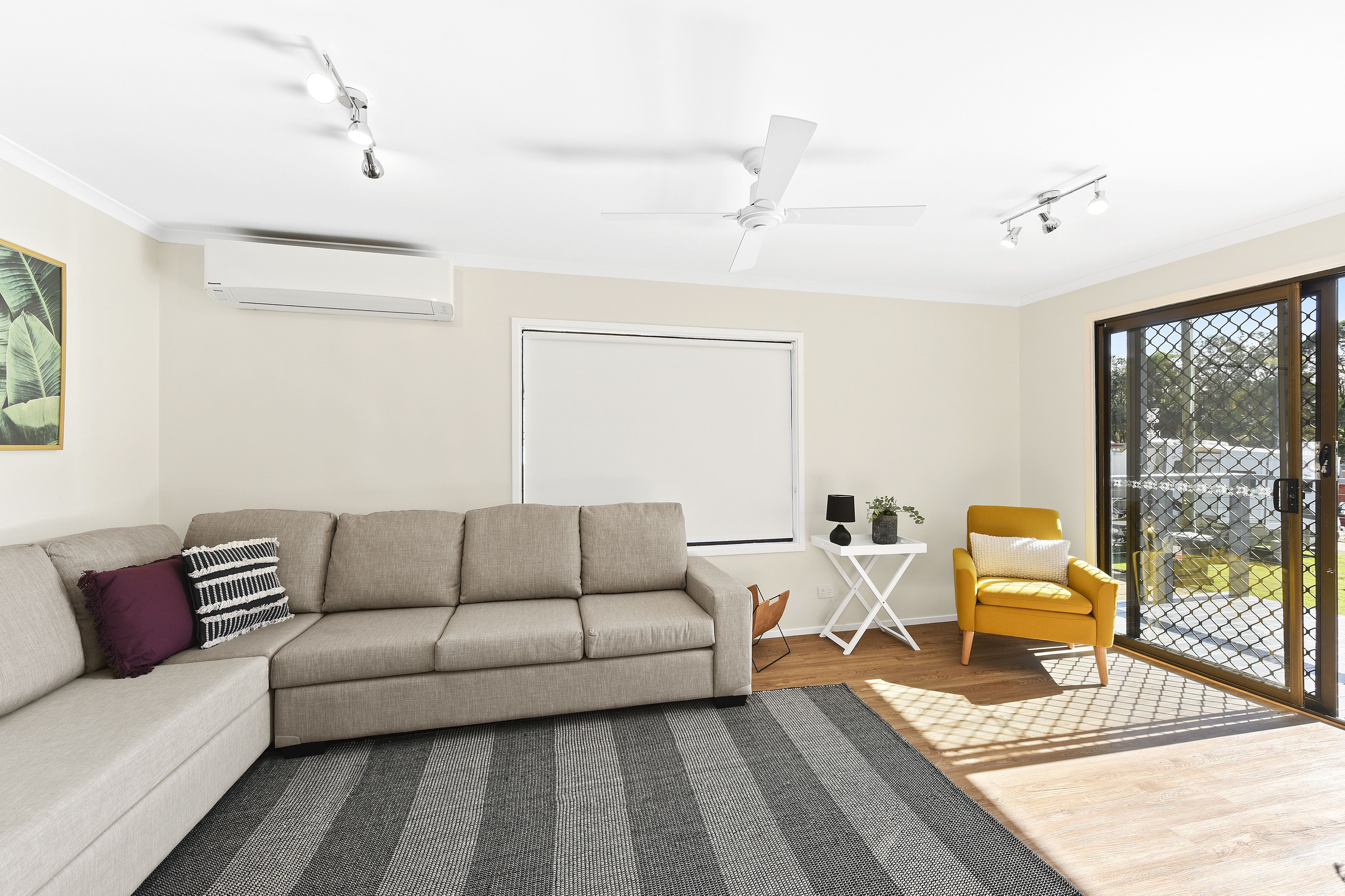 A modern living room with a sofa, armchair, and a large window.