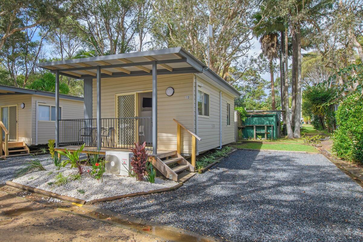 A mobile home with a covered porch and a small front yard.