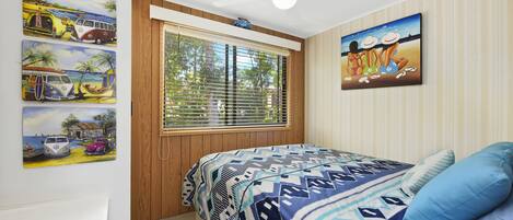 A bedroom with a bed, a window with blinds, a ceiling fan, and wall art.