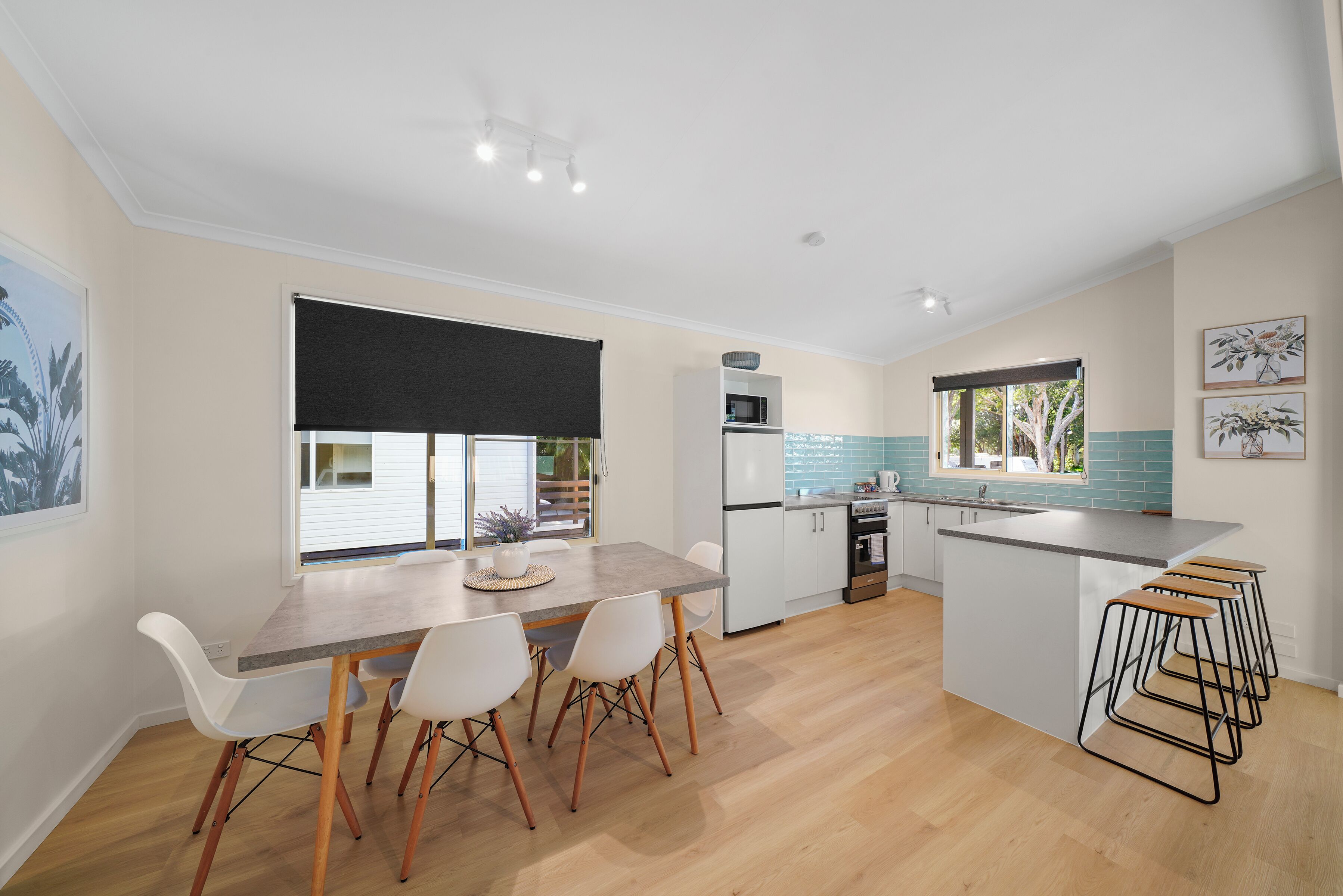 A modern kitchen with a dining area, a large window, and a kitchen island with bar stools.