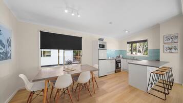 A modern kitchen with a dining area, a large window, and a kitchen island with bar stools.