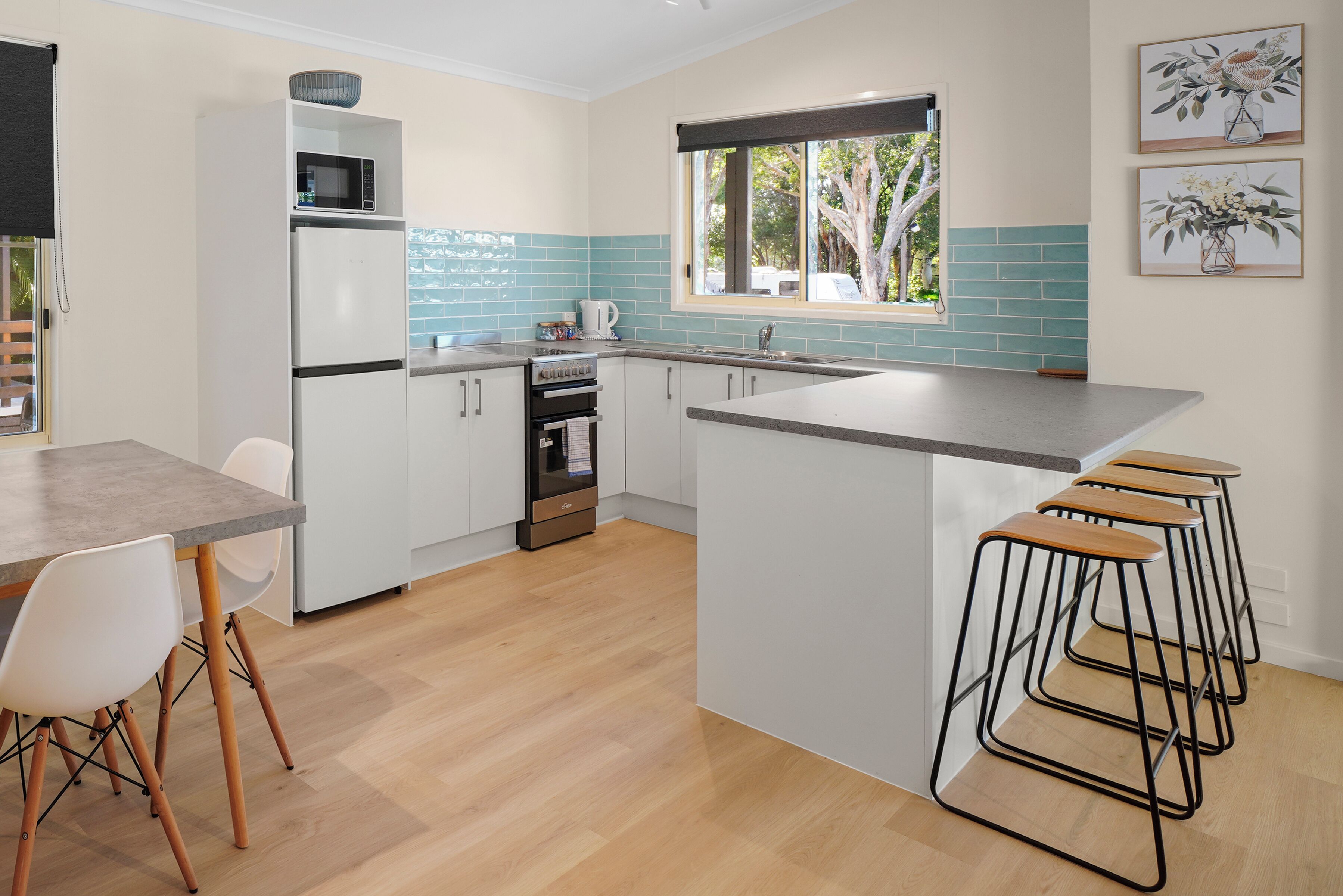 A modern kitchen with a central island, bar stools, and a dining area with a table and chairs.