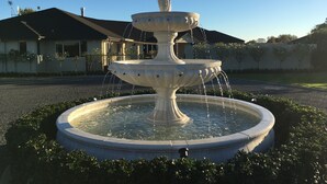 A multi-tiered fountain with water flowing from the top tier, surrounded by a circular stone basin. - Grasslands Bed & Breakfast (Cambridge)