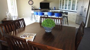 A dining area with a wooden table, chairs, and a central potted plant. - Grasslands Bed & Breakfast (Cambridge)