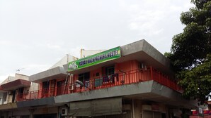 Un hostal con un letrero verde, un balcón rojo y un coche estacionado.
