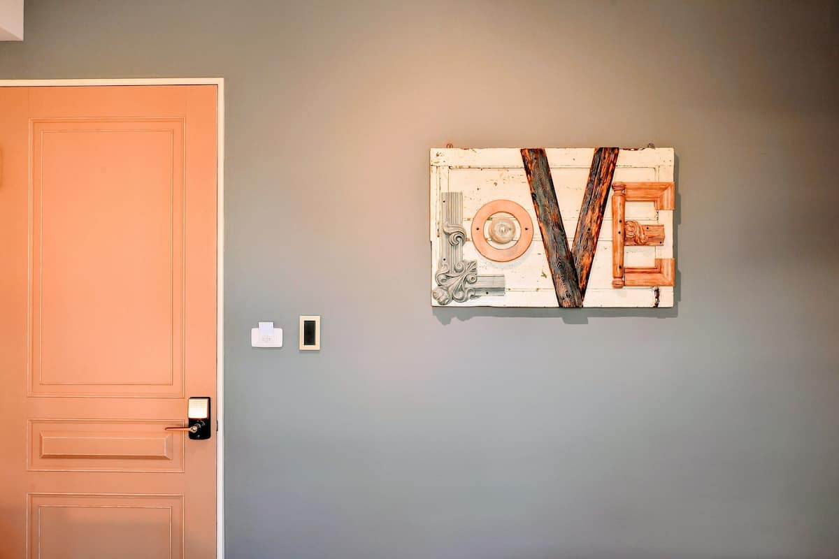 A room with a closed door, a wall-mounted artwork, and a light switch.