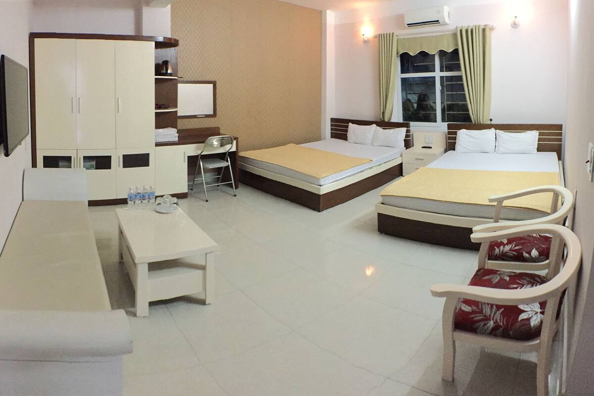 Una habitación de hotel con dos camas, un escritorio, una silla, un televisor y un armario.