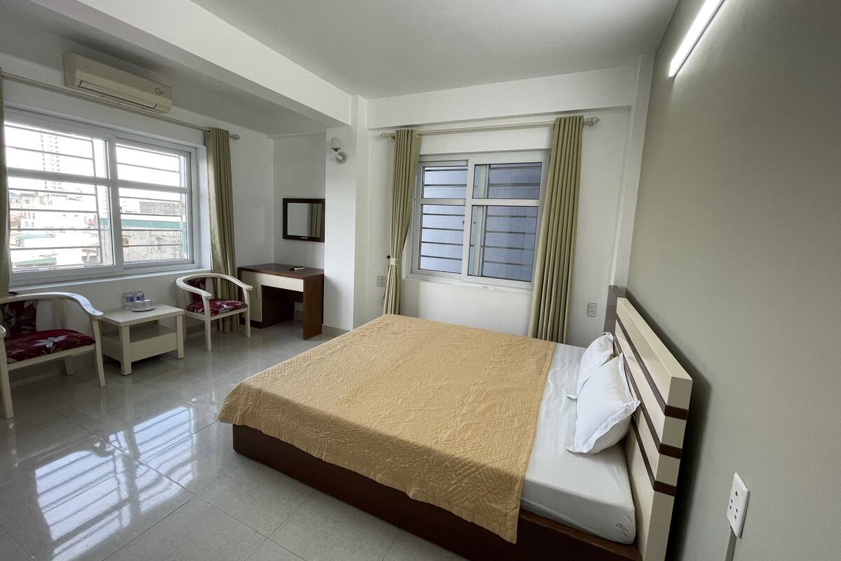 Habitación de hotel con cama, escritorio, silla y ventana.