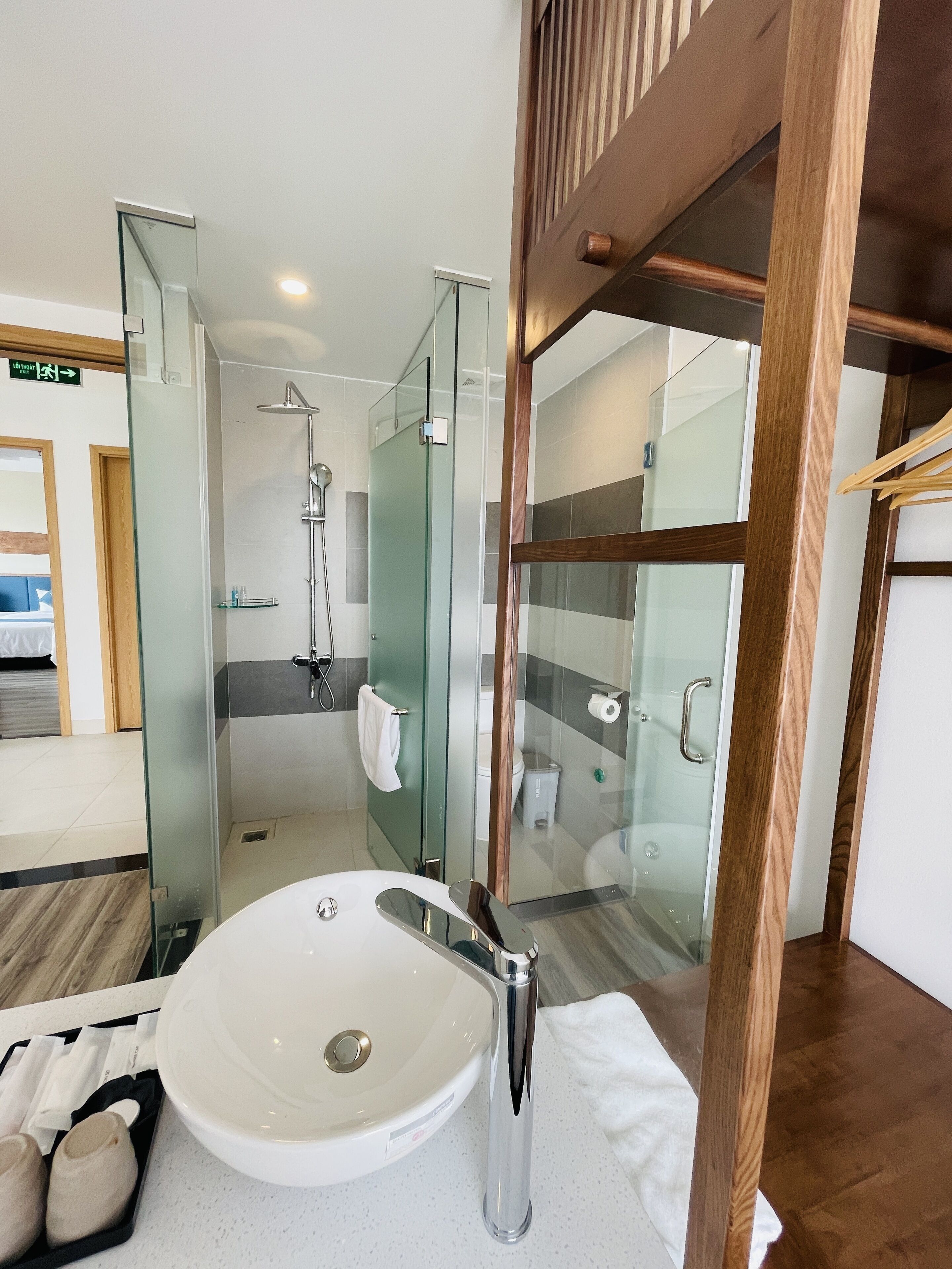 A modern bathroom with a glass-enclosed shower, a white sink, and a wooden floor.