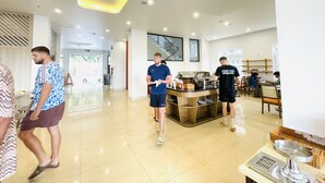 A modern indoor space with a central serving area, a staircase, and a view of the outdoors. - The Light Hotel (Bai Chay)