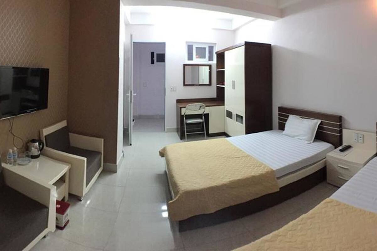 Habitación de hotel con dos camas, un escritorio, un televisor y un armario.