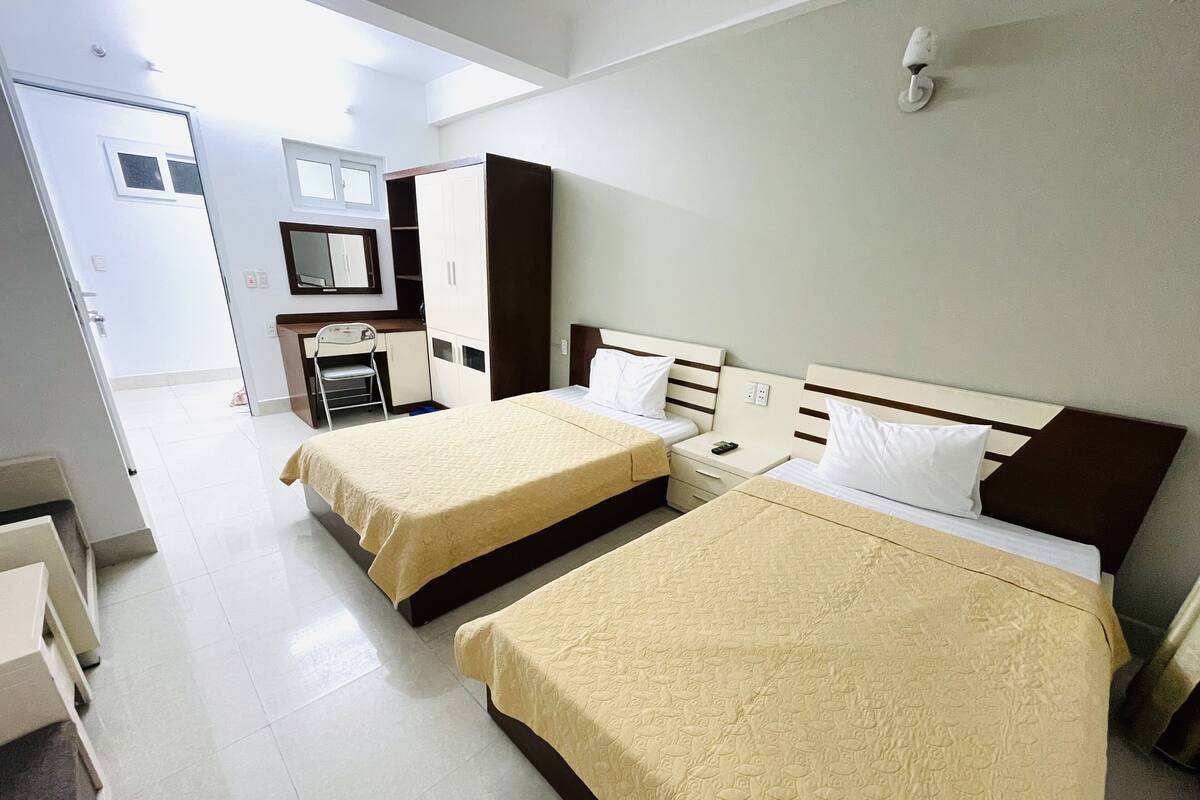 Una habitación de hotel con dos camas, un escritorio, una silla y un armario.