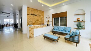 A modern reception area with a wooden wall, a sofa, and a bench. - The Light Hotel (Bai Chay)