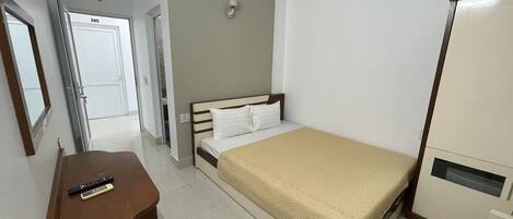 Ein Hotelzimmer mit Bett, Schreibtisch mit Stuhl, Kleiderschrank und einem durchgegangenen Tür angedeuteten Badezimmer.