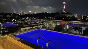A rooftop pool with a clear view of the city skyline at night, including illuminated buildings and a prominent tower. - The Light Hotel (Bai Chay)