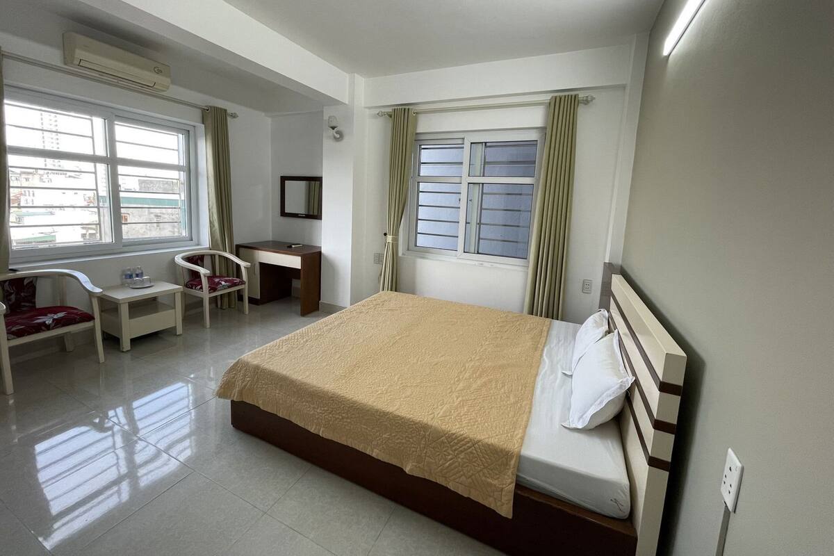 Habitación de hotel con cama, escritorio, silla, ventana y equipo de aire acondicionado.