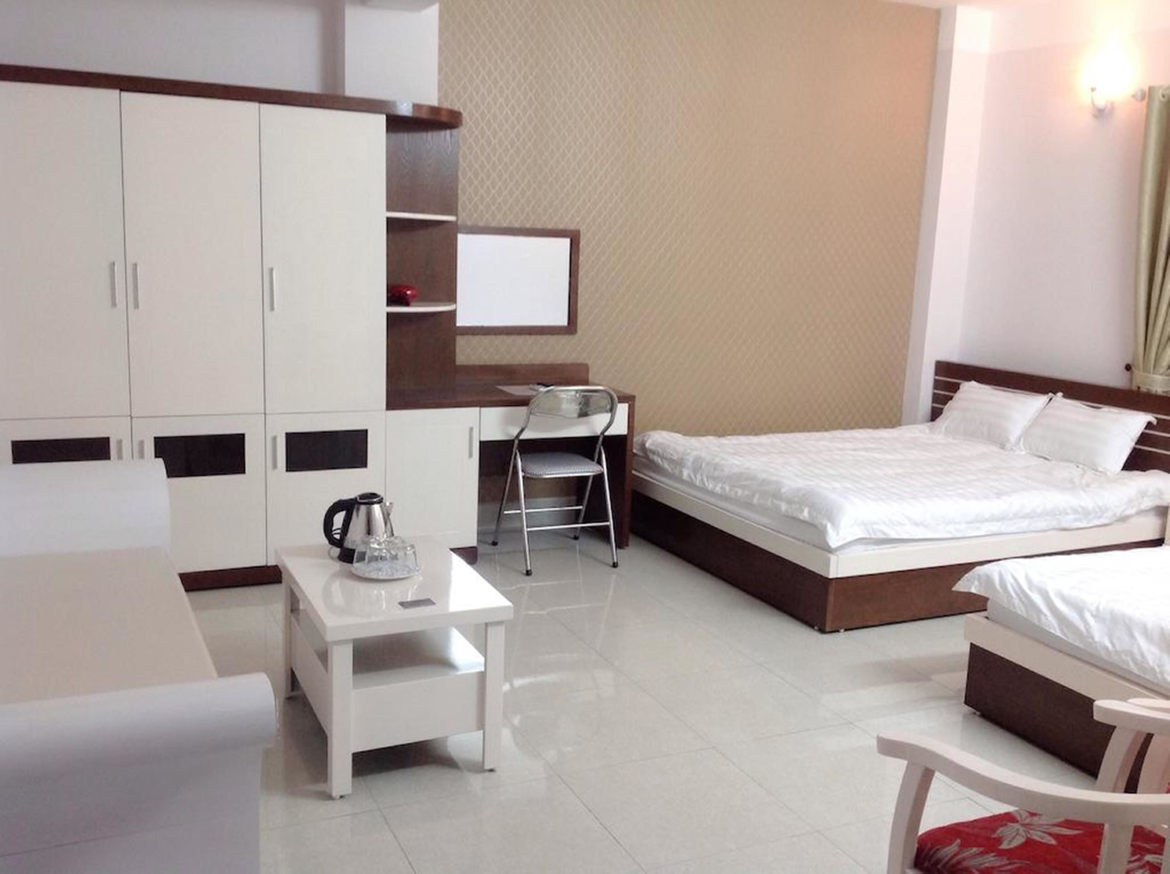 A hotel room with a bed, a desk, a chair, and a wardrobe.