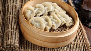 A bamboo steamer filled with dumplings placed on a woven mat. - Zhangjiajie Wang Yi Inn (Zhangjiajie)