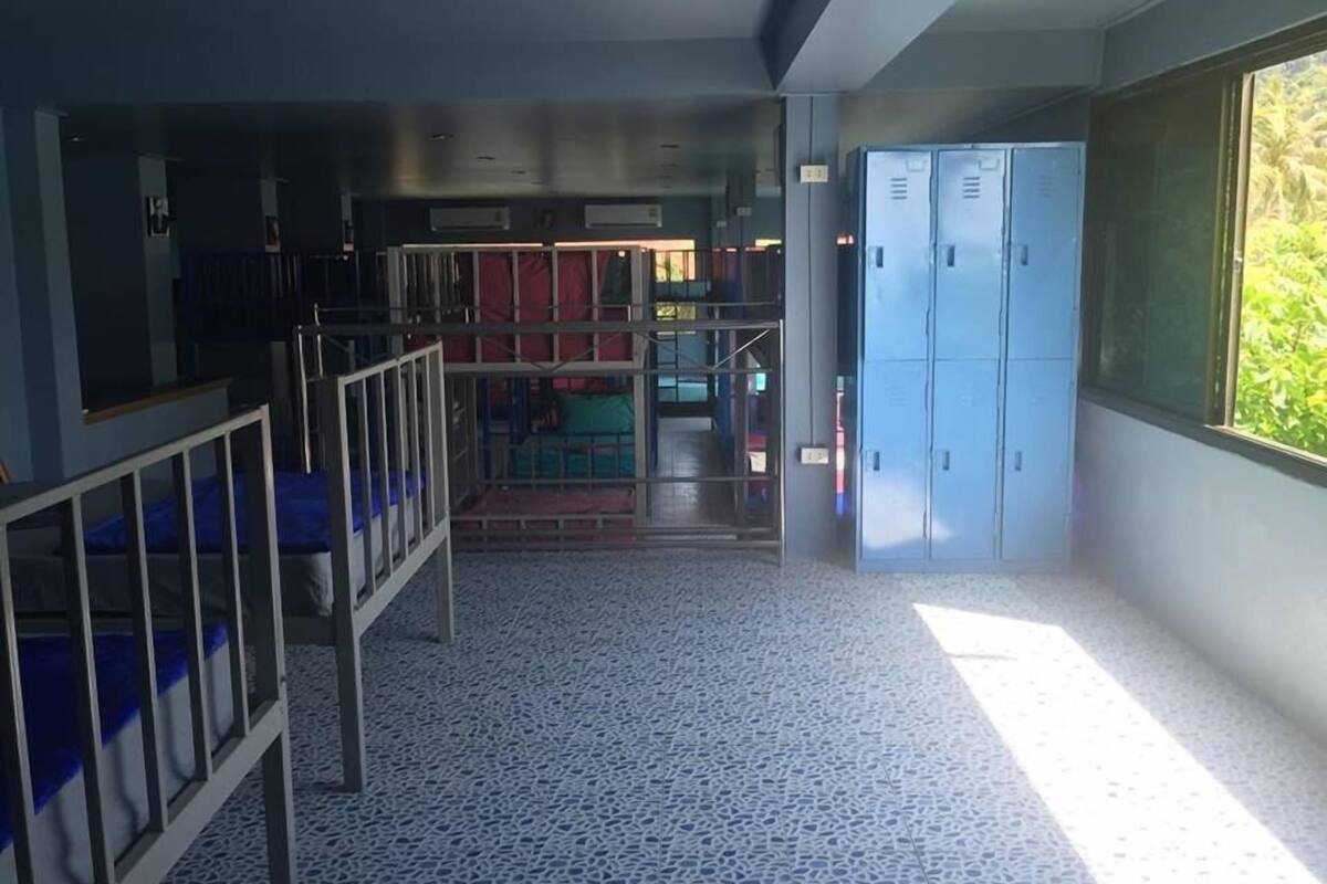 A hallway with a tiled floor, metal railings, and blue lockers on the right.