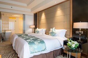A hotel room with a large bed, a bedside table with a lamp, a bathroom with a bathtub, and a mirror.