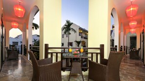 A covered outdoor seating area with wicker furniture and red lanterns, overlooking a building with a balcony. - Little Town Villa (Da Nang)