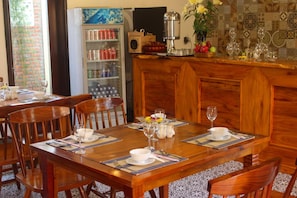 A wooden dining table set with white plates, silverware, and wine glasses, surrounded by wooden chairs. - Little Town Villa (Da Nang)