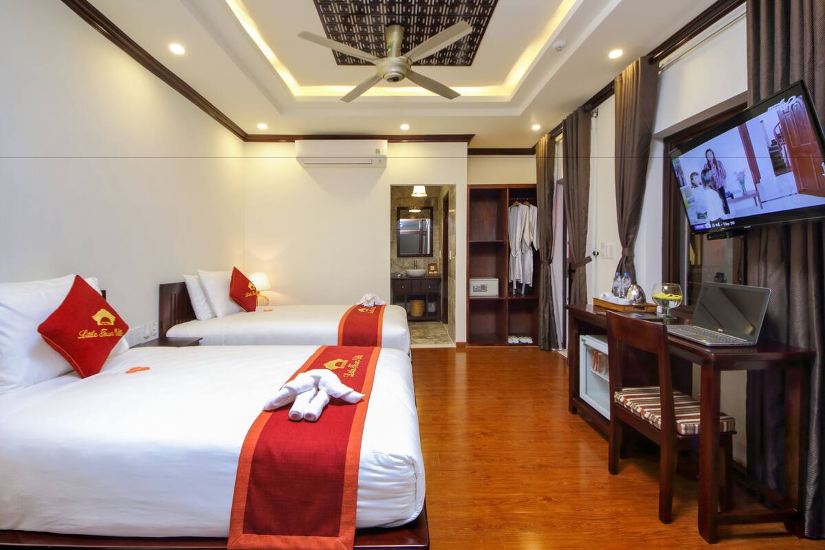 A hotel room with two beds, a television, a desk with a laptop, and a wardrobe.