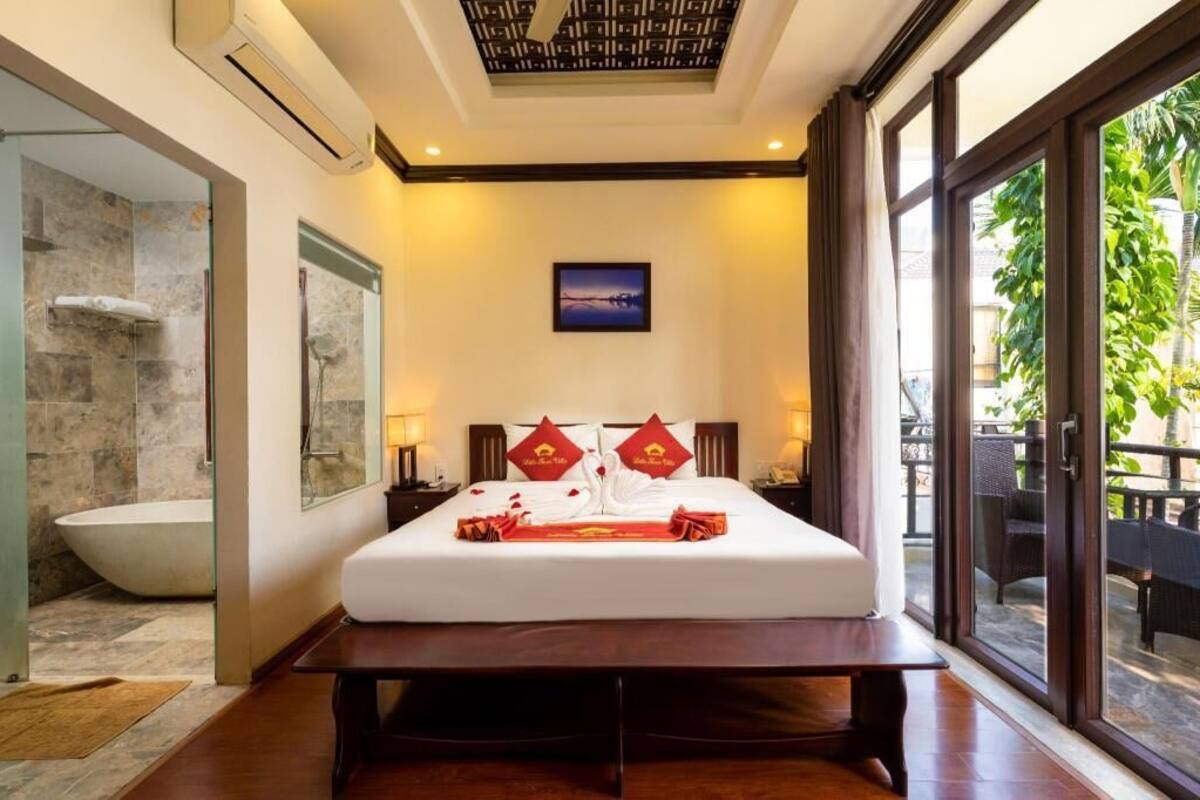 A hotel room with a large bed, a view of the outdoors, a shower, and a dining area.
