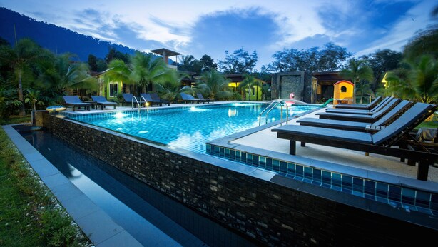 A swimming pool with lounge chairs and a stone wall. - Sirilanta Resort (Ko Lanta)