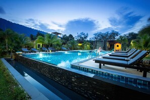 A swimming pool with lounge chairs and a stone wall. - Sirilanta Resort (Ko Lanta)