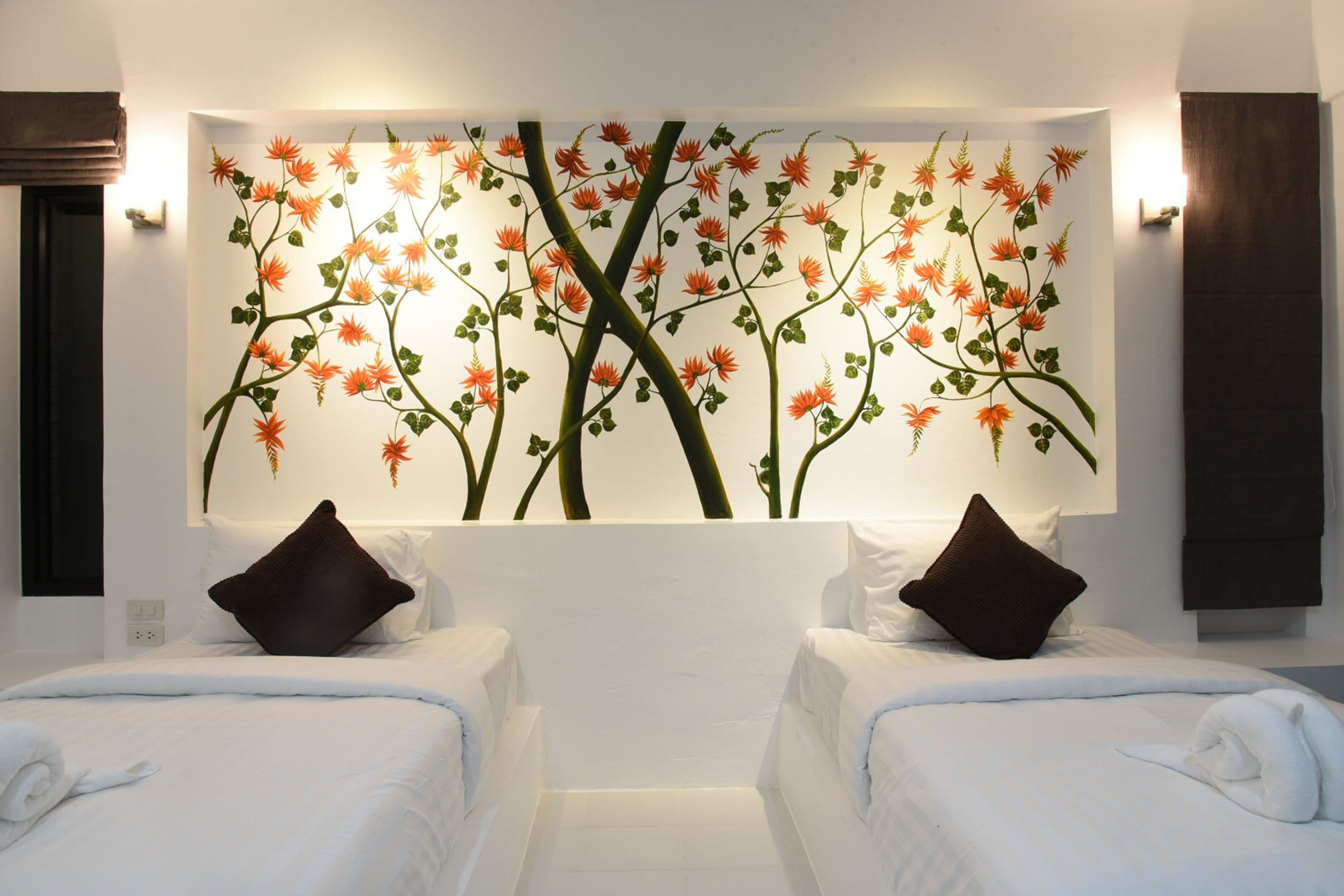 A hotel room with two beds, a large wall mural of orange flowers, and a modern design.