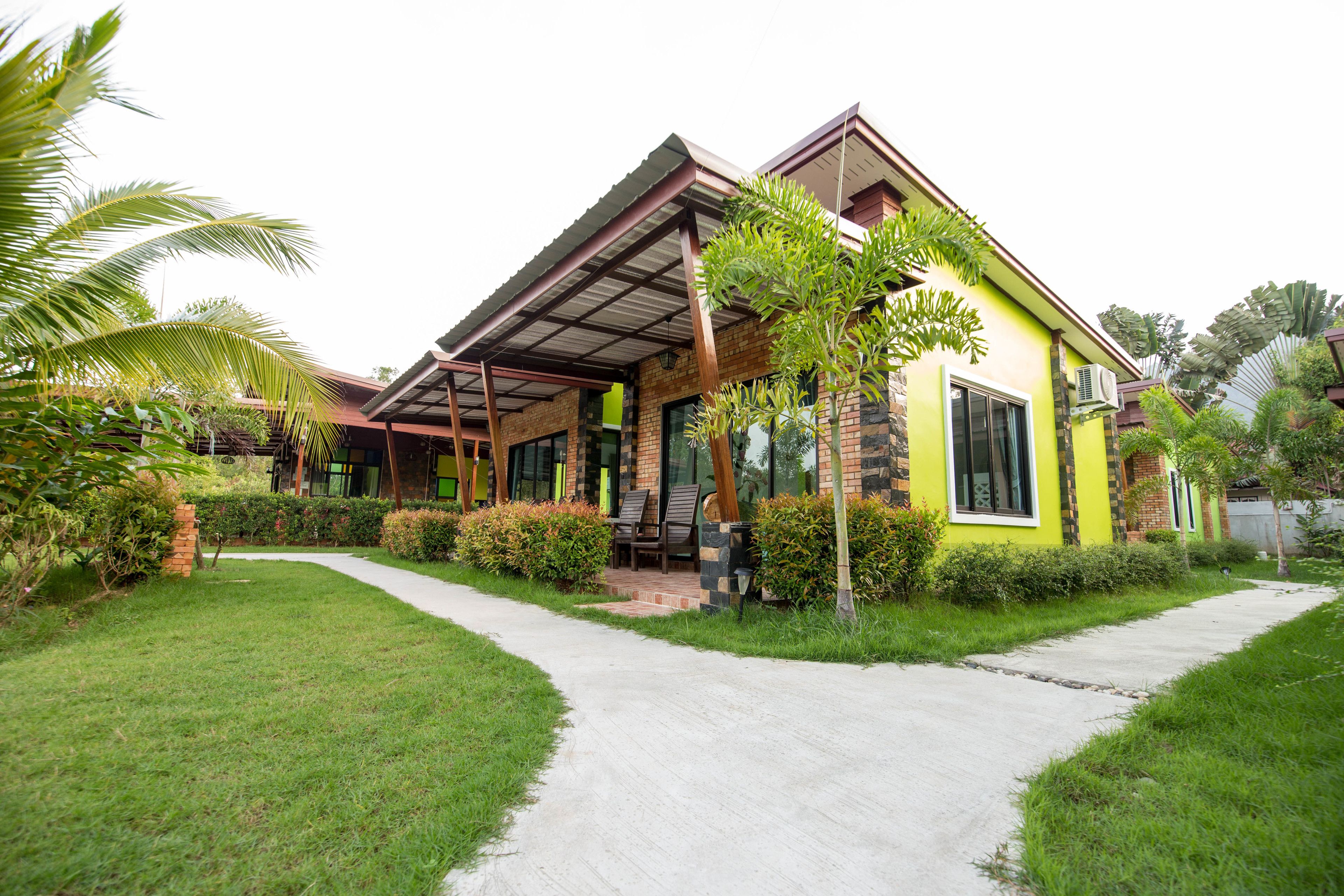 A modern house with a covered porch, a paved walkway, and lush greenery.