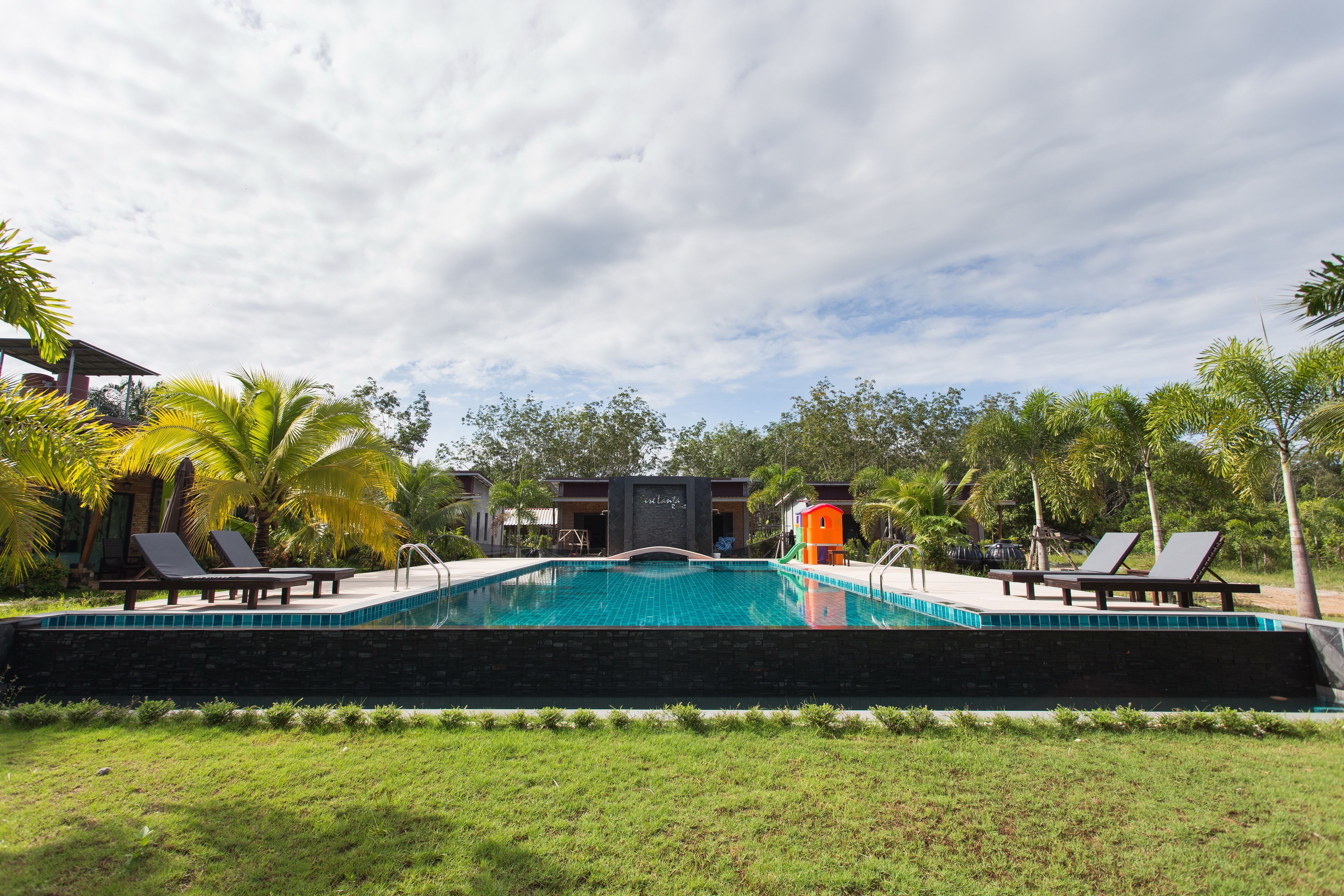 A swimming pool with lounge chairs and palm trees.