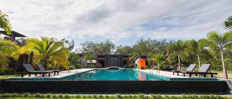 A swimming pool with lounge chairs and palm trees.