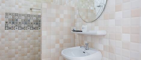 A bathroom with a white sink, a mirror, and a tiled shower area.