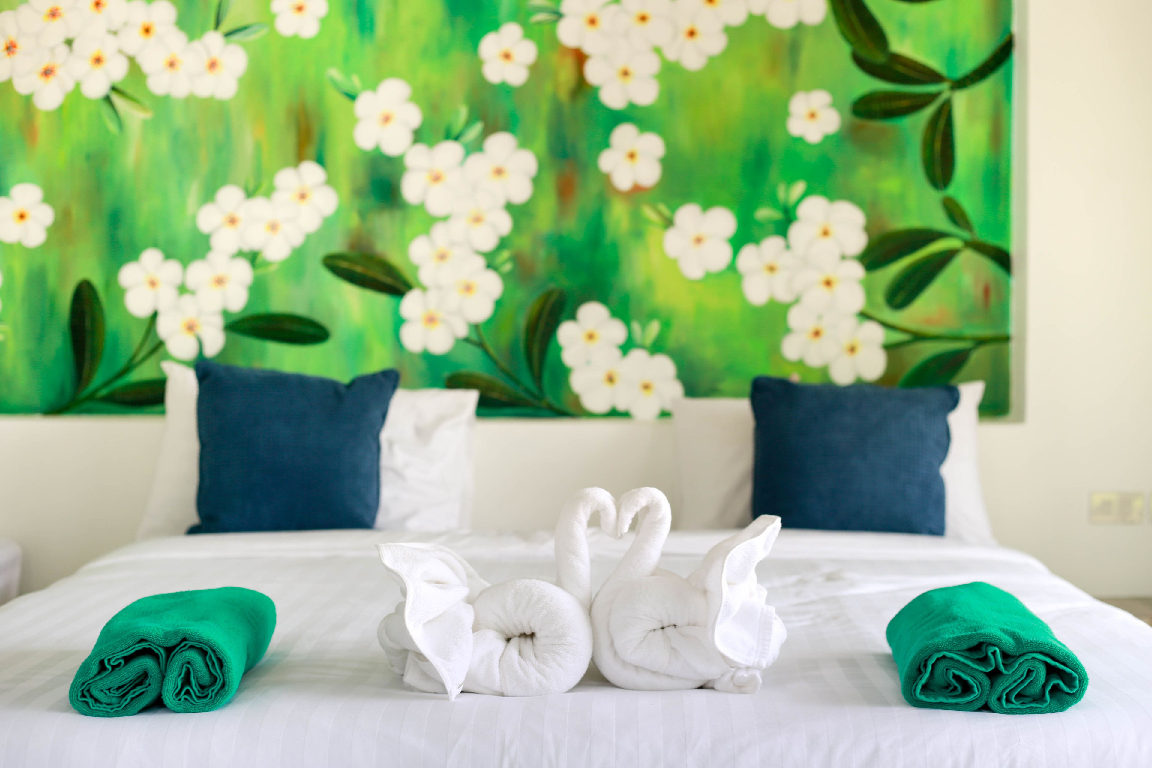 Una habitación de hotel con una cama, dos almohadas y un cuadro de flores en la pared.