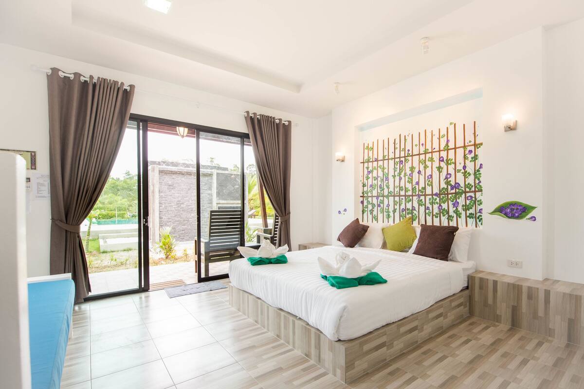 A hotel room with a bed, a desk, a chair, and a view of the outdoors.