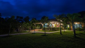 A well-lit building with a pathway leading to it, surrounded by grass and trees. - Sirilanta Resort (Ko Lanta)