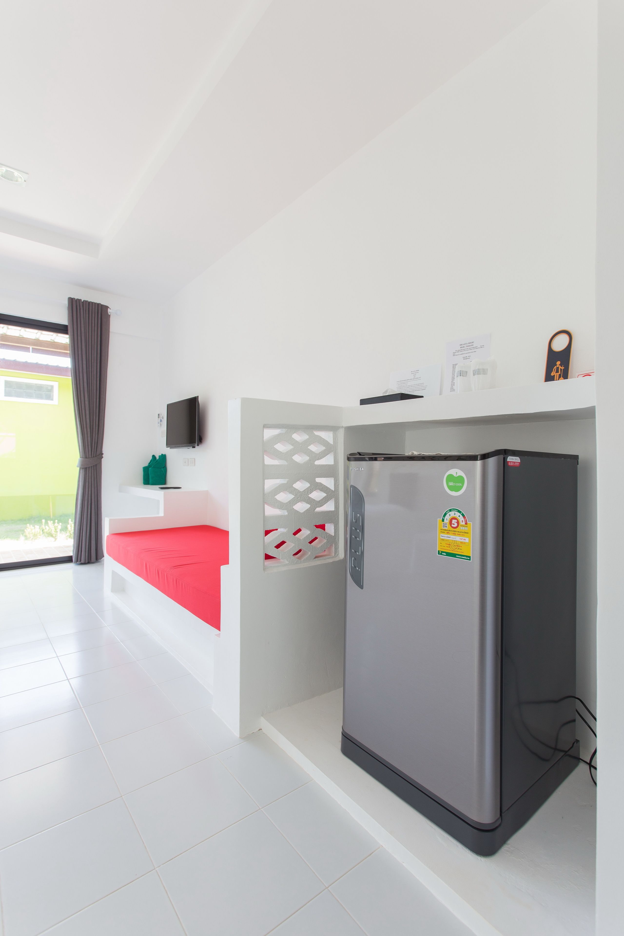 A modern kitchen with a built-in refrigerator, a white countertop, and a window with curtains.