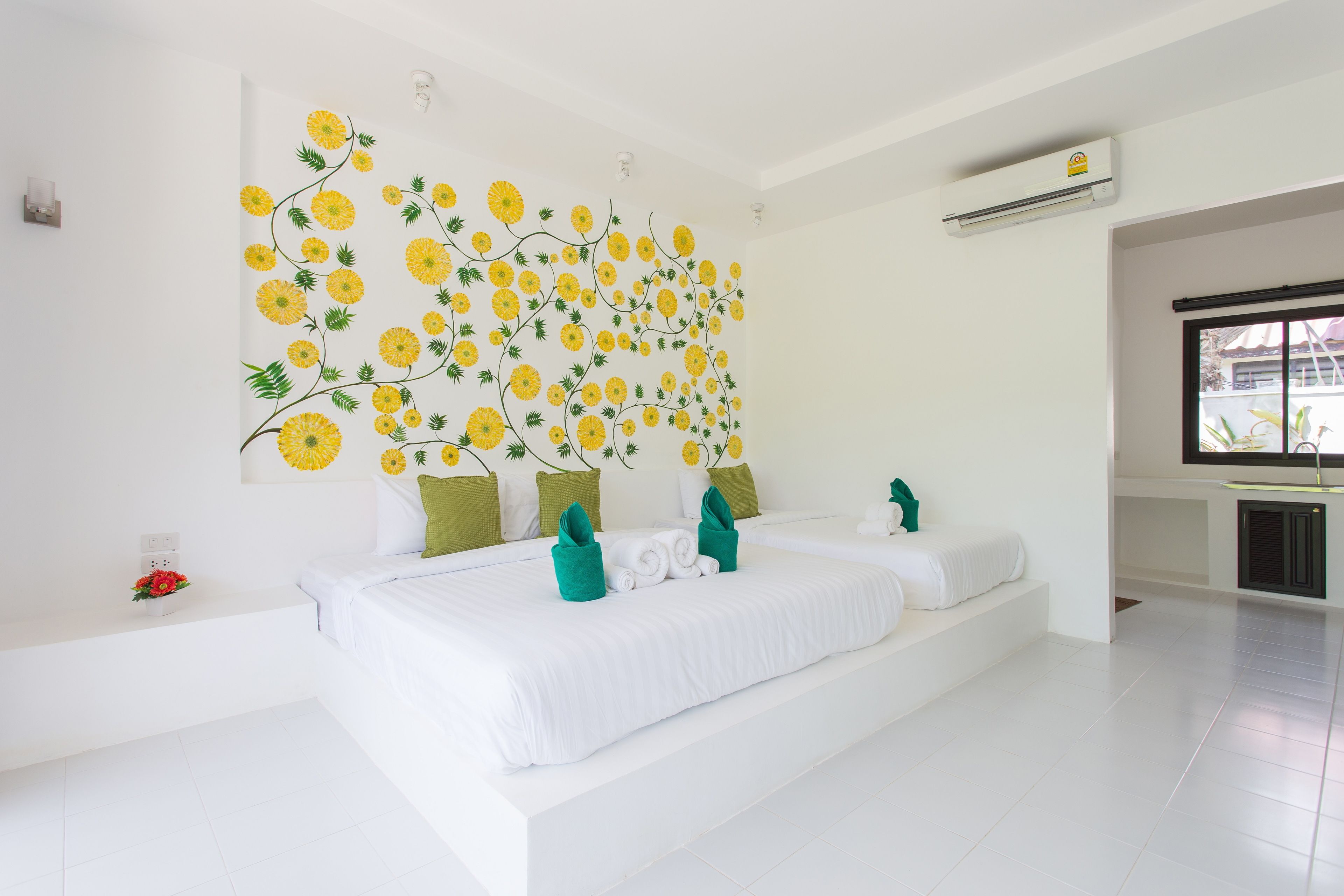 Un dormitorio moderno con una cama grande, paredes blancas y un mural floral.