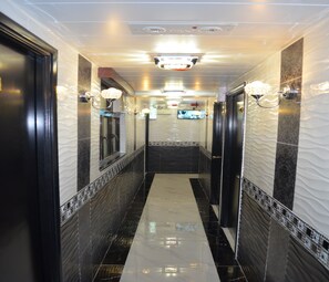 A corridor with black and white patterned walls, a shiny floor, and wall-mounted lights. - Skystar Hostel (Kowloon)