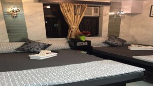 A hotel room with a sofa bed, a bedside table with a lamp, and a window with curtains. - Skyview Hostel (Kowloon)