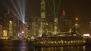 A cruise ship docked at a port with a city skyline in the background. - Skyview Hostel (Kowloon)