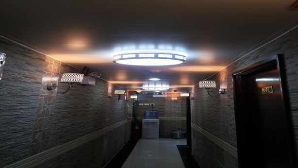 A hallway with patterned walls, a water dispenser, and a door with a brass handle. - Skyview Hostel (Kowloon)