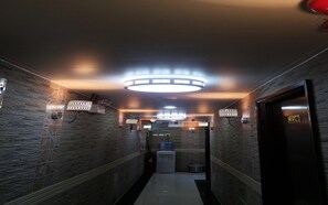 A hallway with patterned walls, a water dispenser, and a door with a brass handle. - Skyview Hostel (Kowloon)