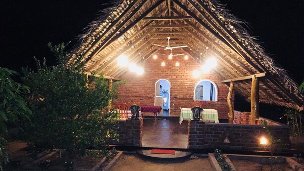 A rustic building with a thatched roof, brick walls, and a central open area with seating. - Winmi Resort (Habarana)