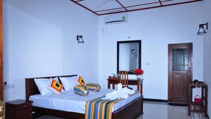 A bedroom with a bed, bedside table, mirror, and a door. - Winmi Resort (Habarana)