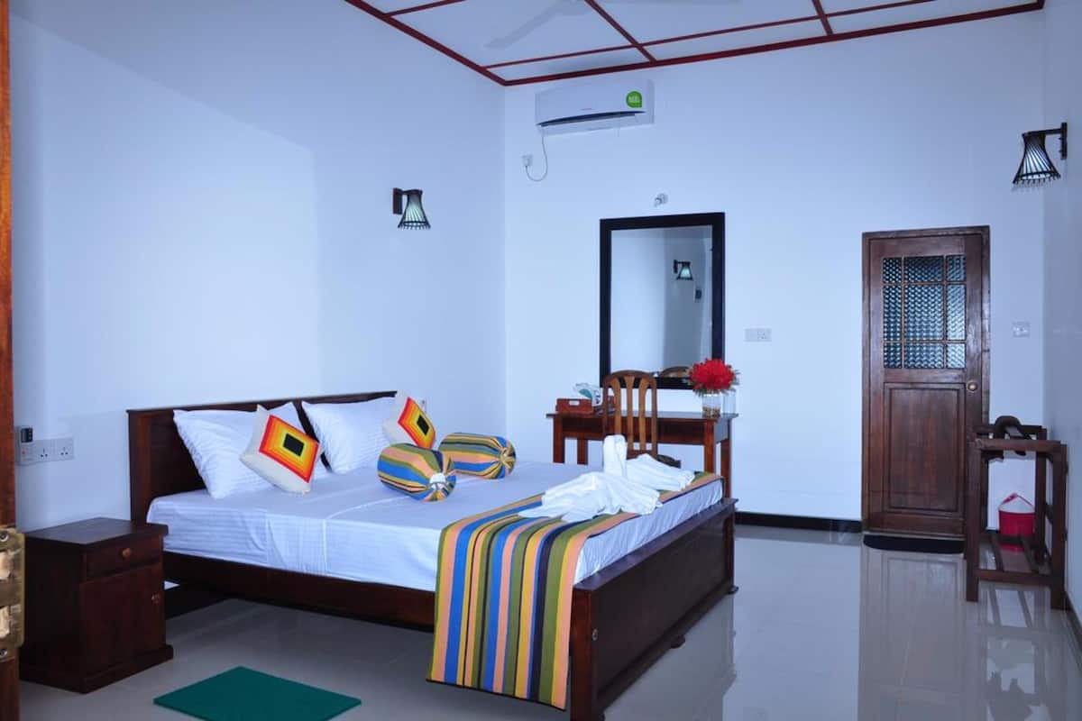 A bedroom with a bed, bedside table, mirror, and a door.