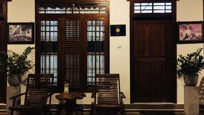 A traditional wooden door with a glass panel, flanked by two potted plants, and a bench with a small table in front. - Winmi Resort (Habarana)