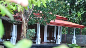 A traditional building with a red roof, white columns, and wooden doors. - Winmi Resort (Habarana)